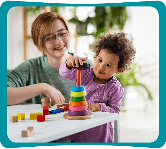 Child stacking colorful rings with adult supervision.