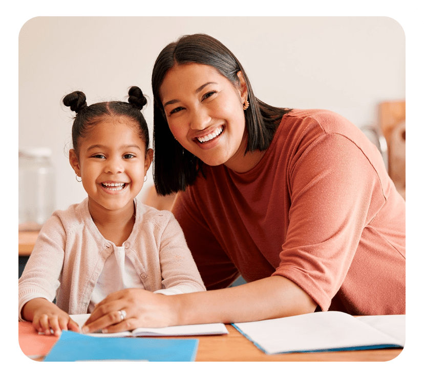 Smiling woman and girl at table together.